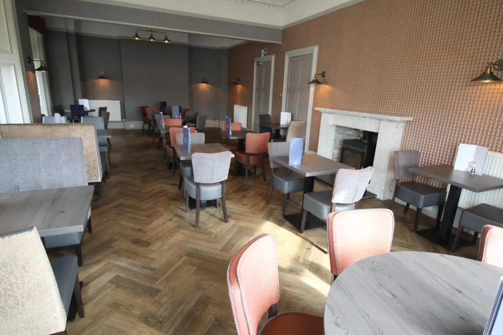 a restaurant with tables and chairs and a fireplace at The Royal Hotel Elgin in Elgin