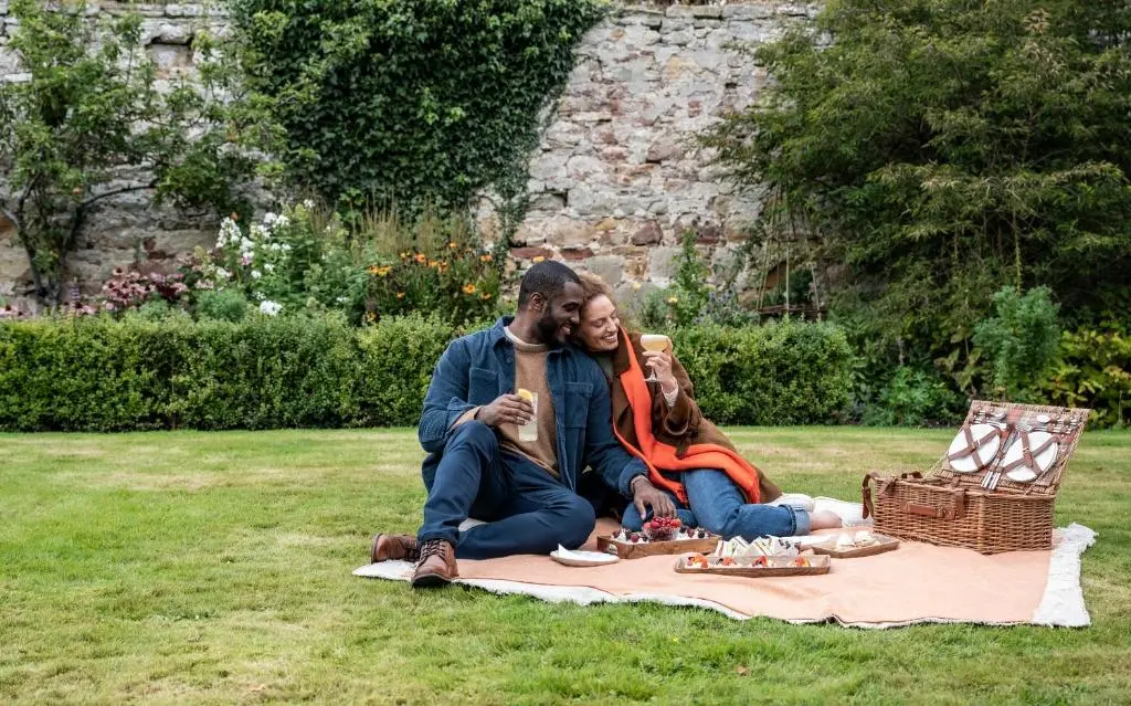 two people sitting on a picnic blanket in the grass at The Glenmorangie House in Tain
