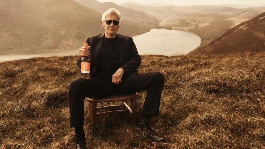 a man sitting in a chair holding a bottle of beer at The Glenmorangie House in Tain