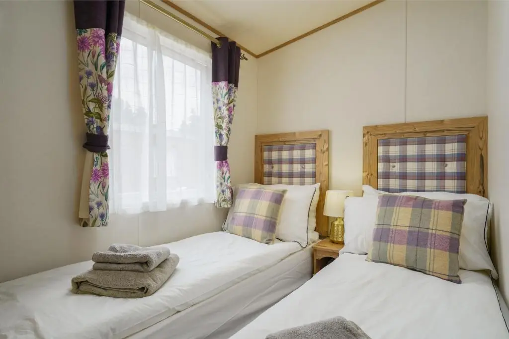 a bedroom with two beds and a window at Dunroamin Lodge in Aviemore