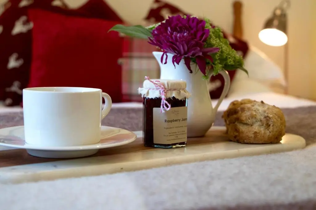 a table with a coffee cup and a vase with flowers at Tanar View in Aboyne