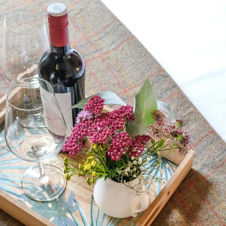 a wooden tray with a bottle of wine and flowers at Tanar View in Aboyne