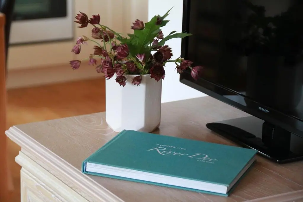 a book and a vase with flowers on a desk at Tanar View in Aboyne
