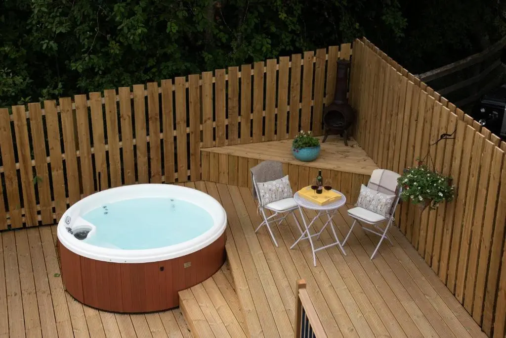 a hot tub on a deck with a table and chairs at Tanar View in Aboyne
