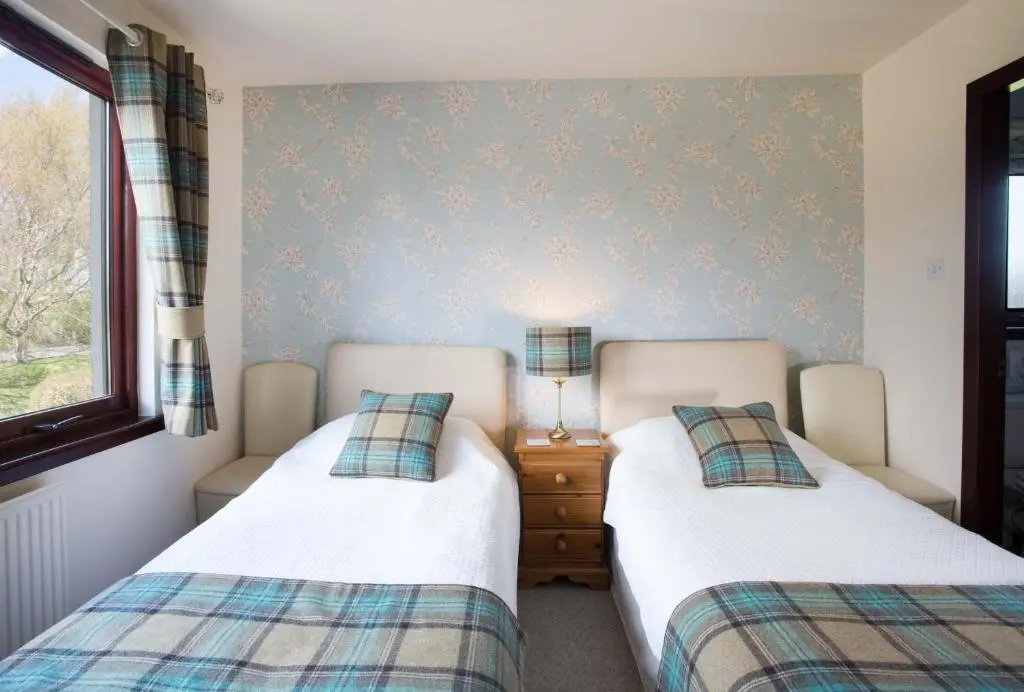 a bedroom with two beds and a window at Leanach Farm in Inverness