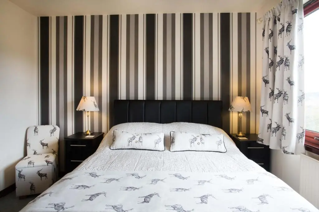 a bedroom with a bed with two lamps and a chair at Leanach Farm in Inverness