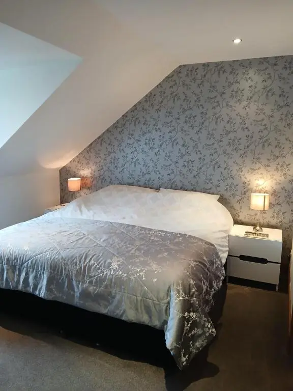a bedroom with a large bed with a floral wallpaper at Holiday House Kinveachy in Aviemore