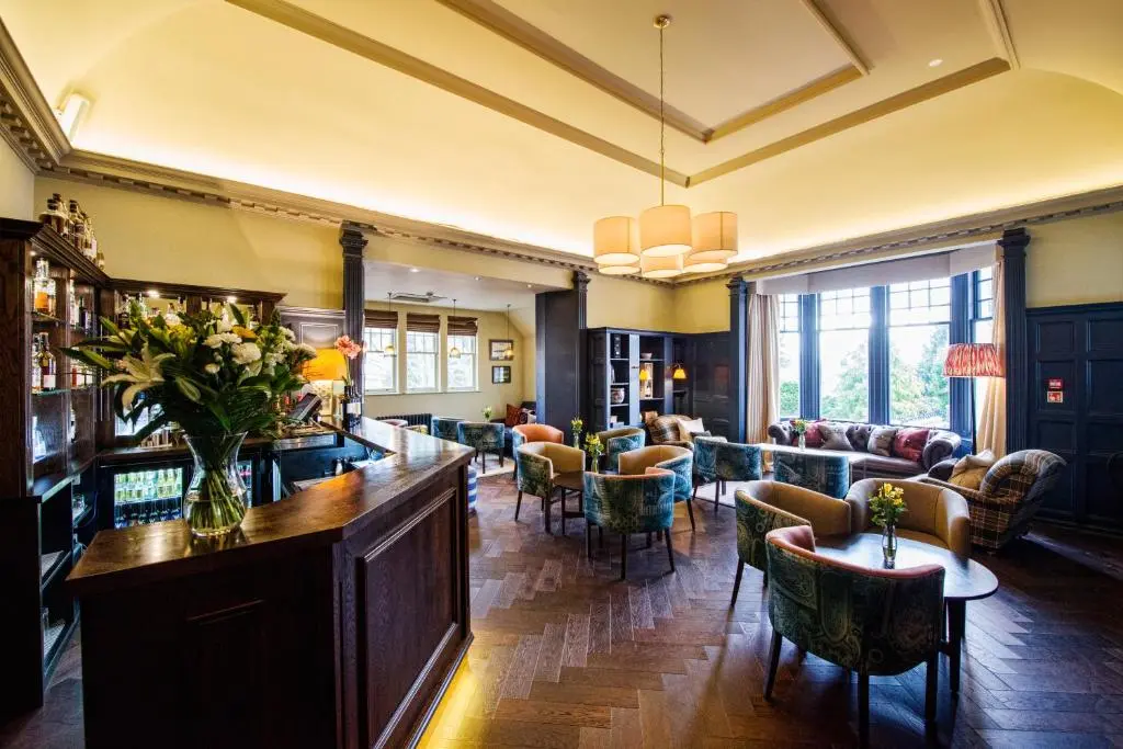 a hotel lobby with a bar and chairs at Douneside House in Tarland