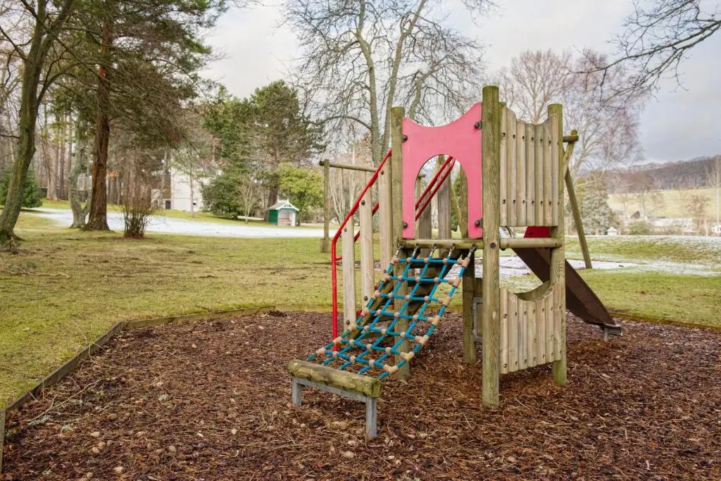 a playground with a slide in a park at Douneside House in Tarland