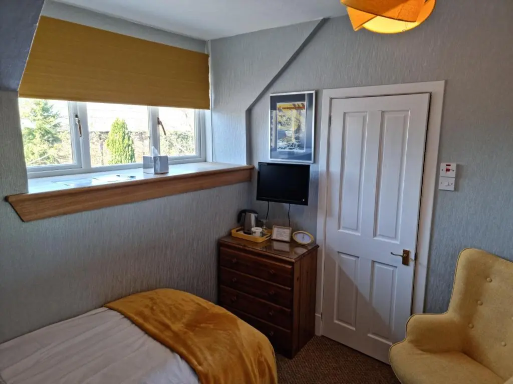 a bedroom with a bed and a television and a chair at Drumdale Bed and Breakfast in Inverness