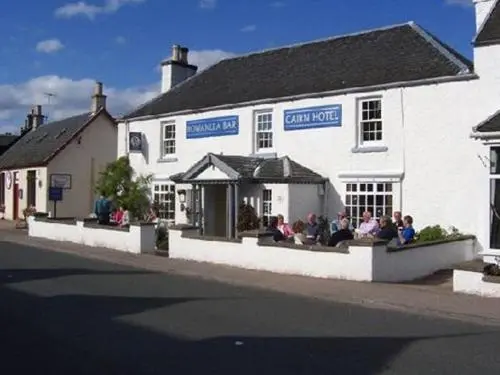 a group of people sitting outside of a white building at Cairn Hotel in Carrbridge