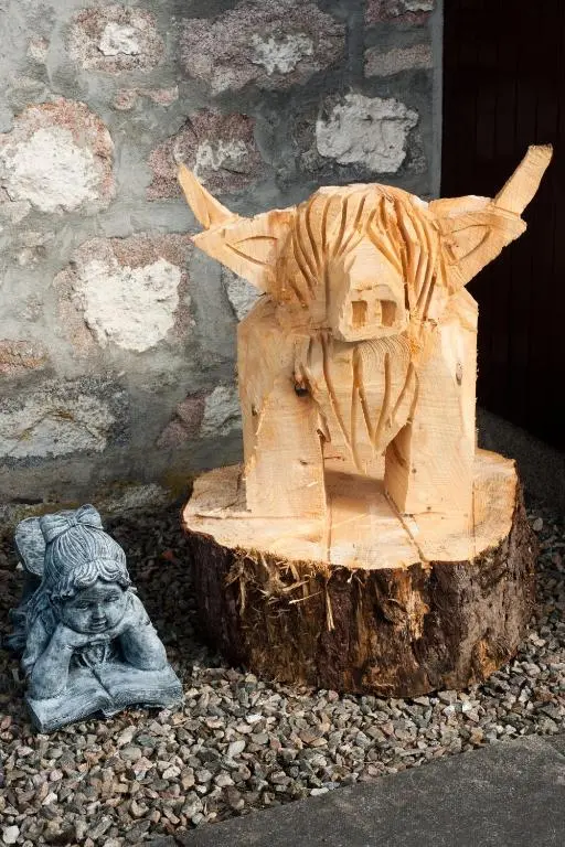a wooden carving of a lion on a tree stump at Strathspey Cottage in Carrbridge