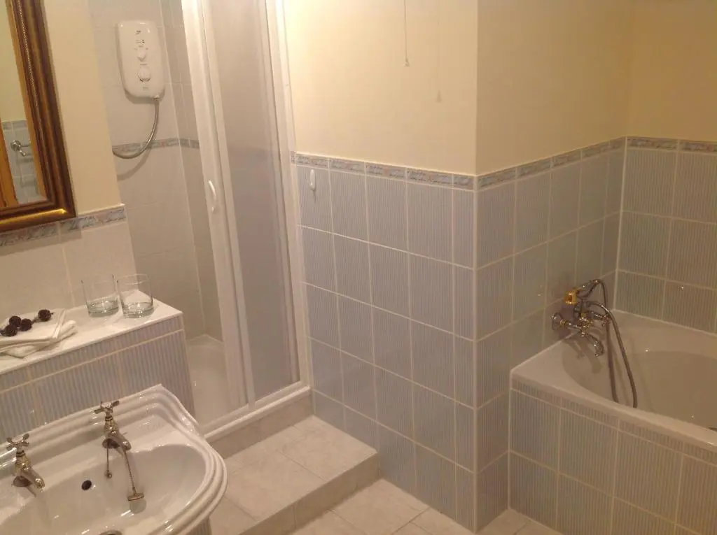 a bathroom with a shower and a tub and a sink at Lochview Guesthouse in Contin