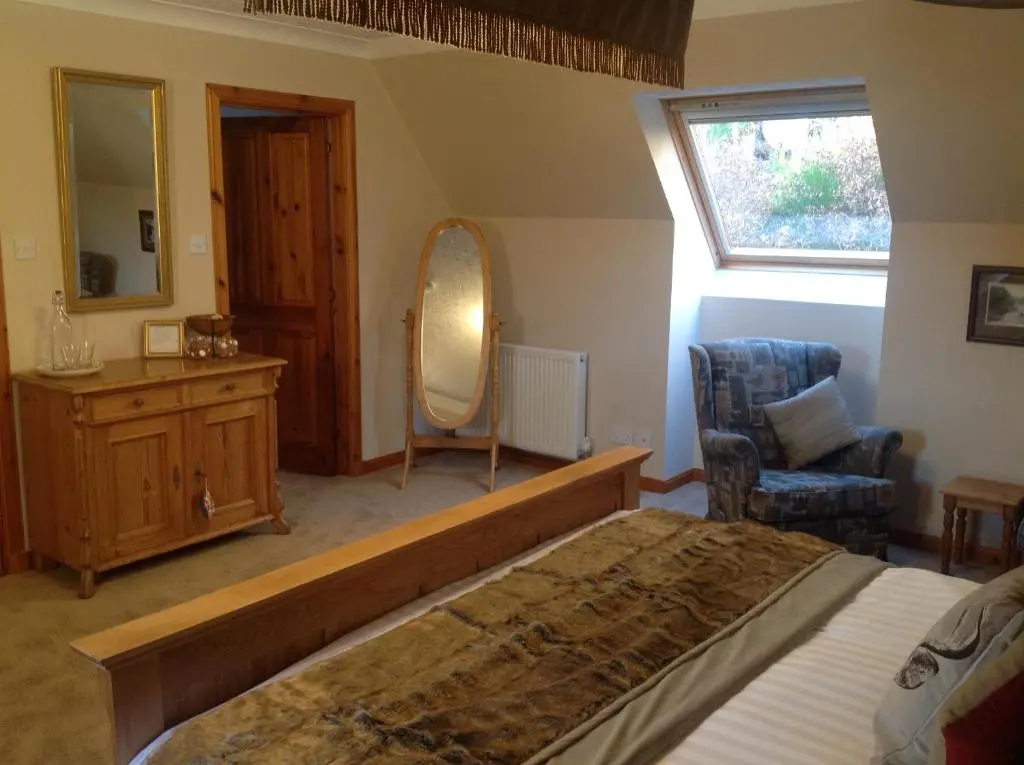 a bedroom with a bed and a mirror and a chair at Lochview Guesthouse in Contin