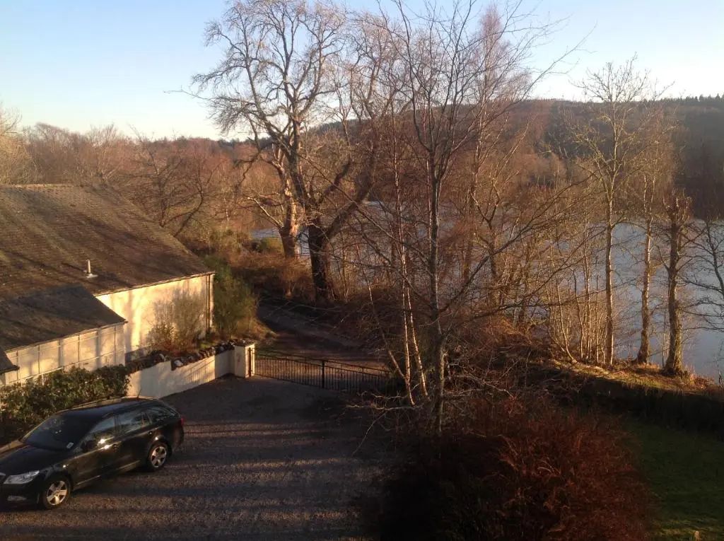 a car parked next to a building next to a river at Lochview Guesthouse in Contin