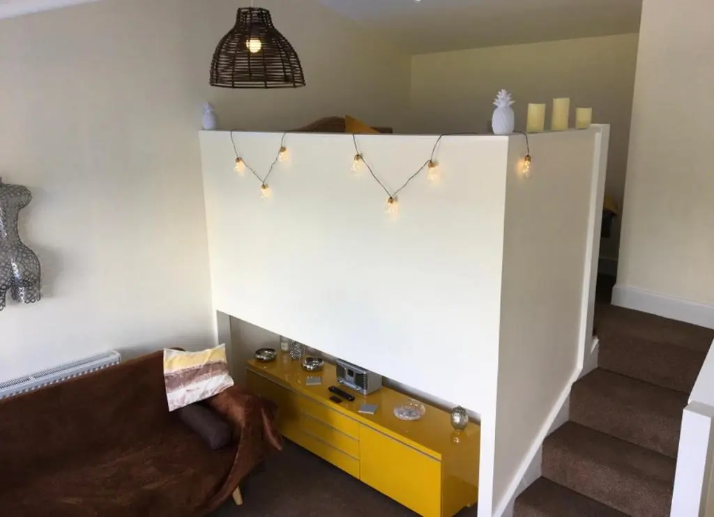 a living room with a yellow cabinet and stairs at Bankhead Accommodation Aberdeenshire in Gamrie