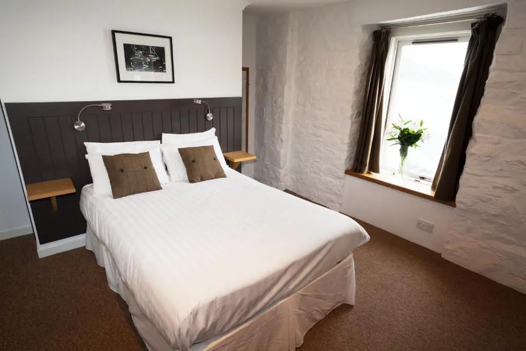 a bedroom with a large white bed and a window at The Arch Inn in Ullapool