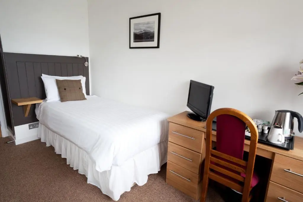 a bedroom with a bed and a desk with a television at The Arch Inn in Ullapool
