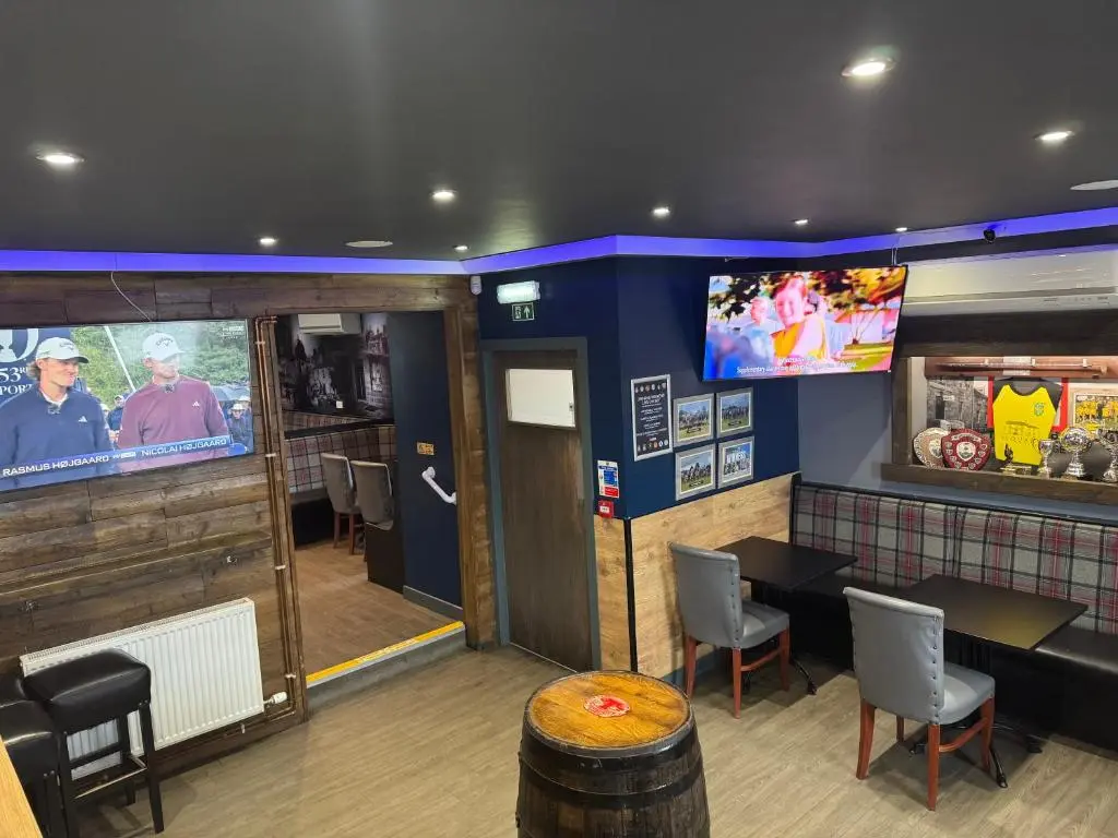 a restaurant with a table and chairs and a tv at The Square Kintore in Kintore