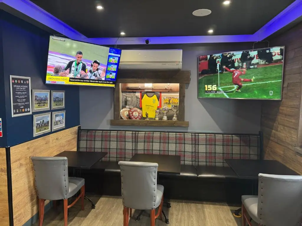 a restaurant with two televisions on the wall and tables at The Square Kintore in Kintore
