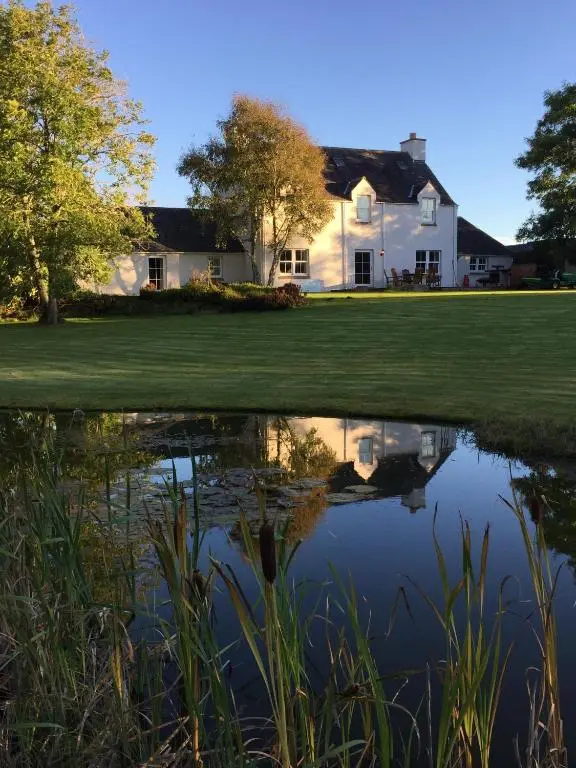 a house with a reflection in a pond at The Annex - Easter Arr in Auldearn