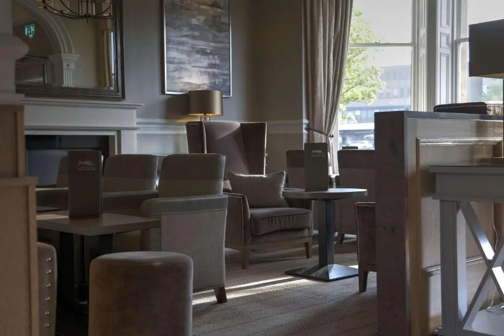 a waiting room with chairs and tables and a fireplace at Inverness Palace Hotel & Spa, WorldHotels Distinctive in Inverness
