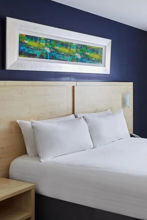 a bed with white pillows and a picture above it at Leonardo Inn Aberdeen Airport in Dyce