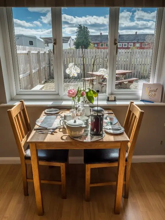 a dining room table with chairs and a table and a window at The Birches in Dingwall