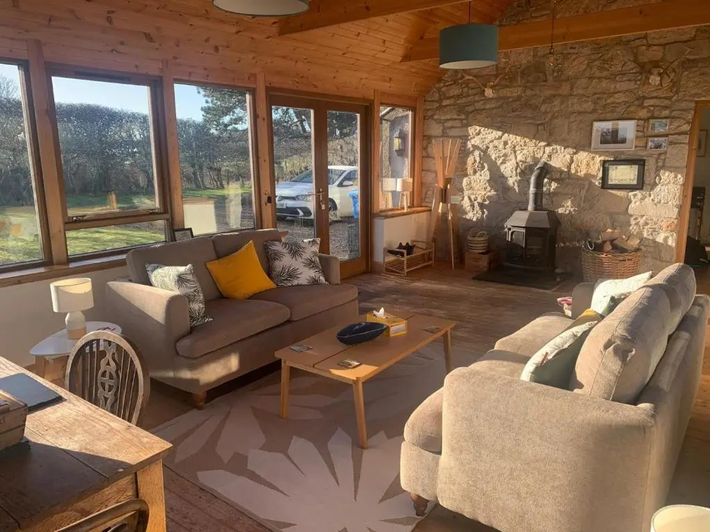 a living room with two couches and a fireplace at Auchencairn Cottage in Brora