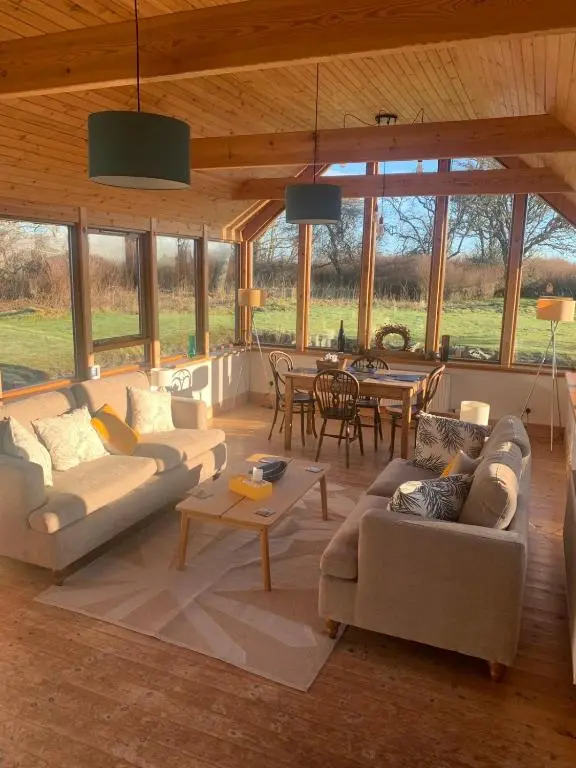 a living room with couches and a dining room at Auchencairn Cottage in Brora