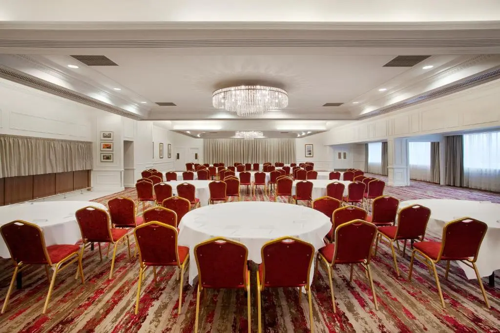 a conference room with white tables and red chairs at Leonardo Hotel and Conference Venue Aberdeen Airport in Dyce