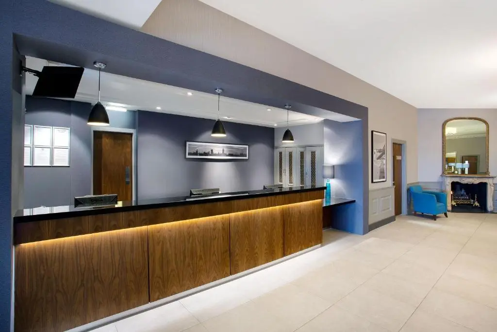 a lobby with a bar with blue walls at Leonardo Hotel and Conference Venue Aberdeen Airport in Dyce