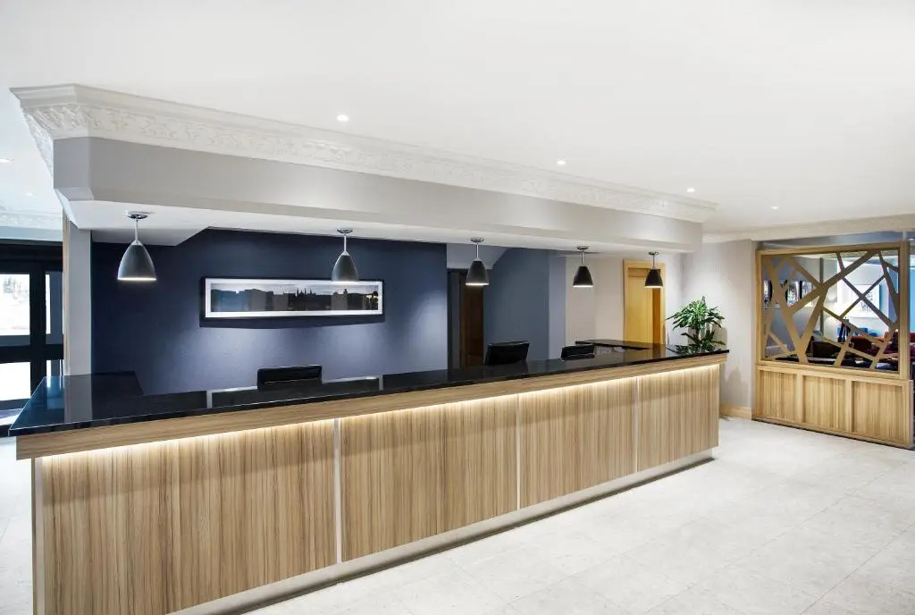 a lobby with a bar with blue walls at Leonardo Hotel Inverness in Inverness