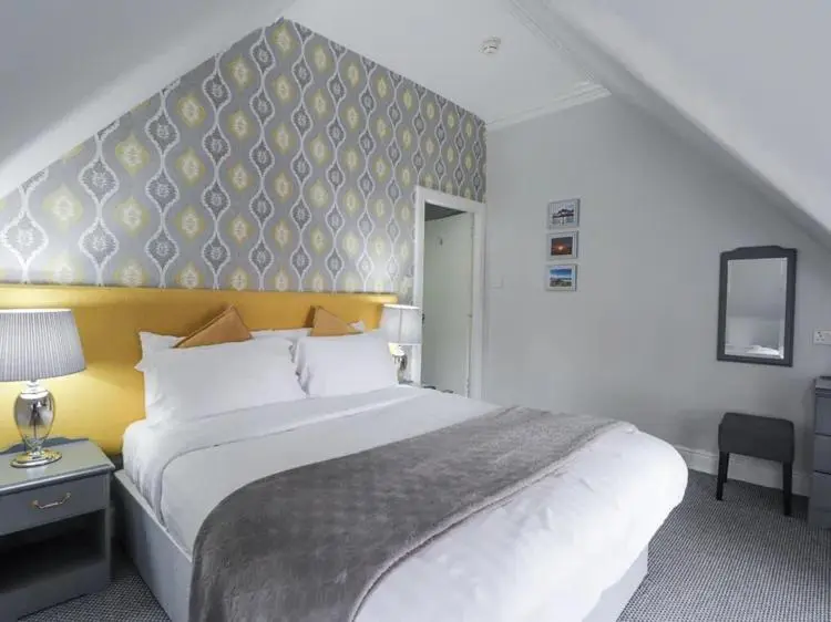 a bedroom with a large white bed with a yellow headboard at McInnes House rooms with breakfast in Kingussie