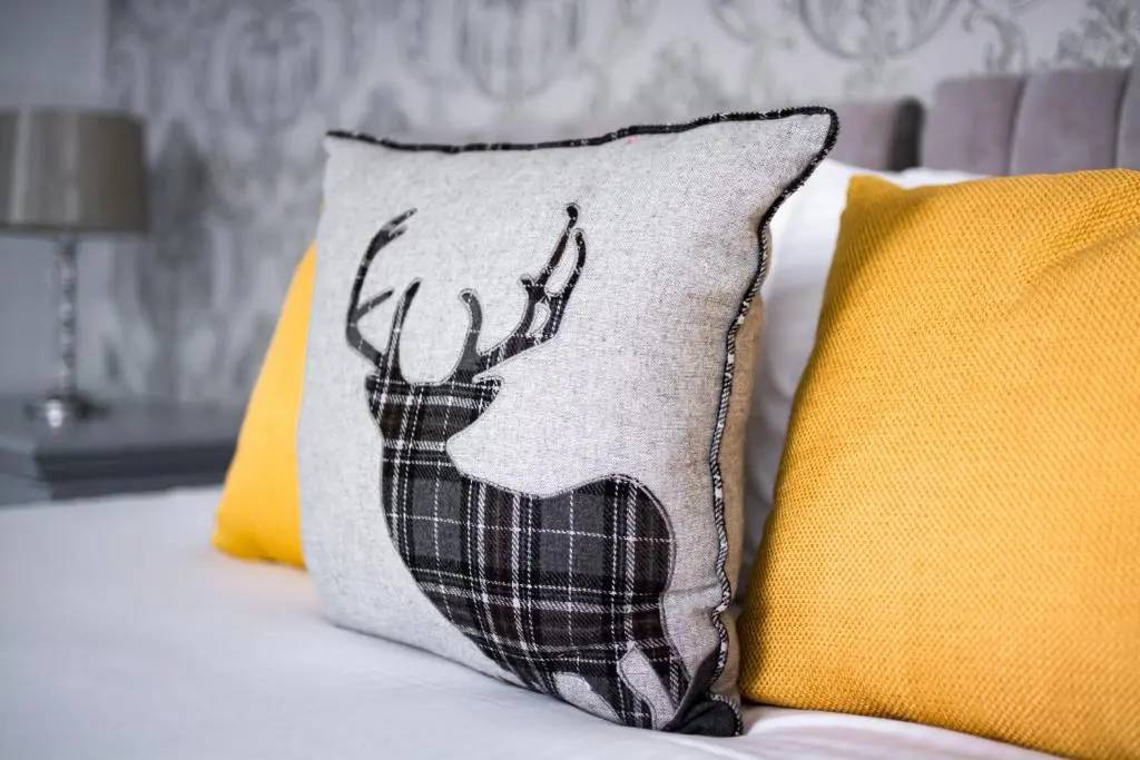 a pillow with a deer on it next to two pillows at McInnes House rooms with breakfast in Kingussie
