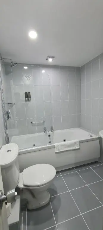 a white bathroom with a toilet and a bath tub at McInnes House rooms with breakfast in Kingussie