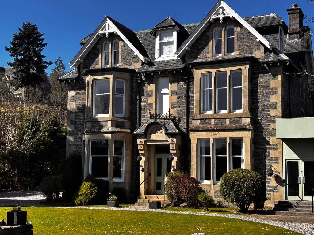 a large brown brick house with a front yard at McInnes House rooms with breakfast in Kingussie