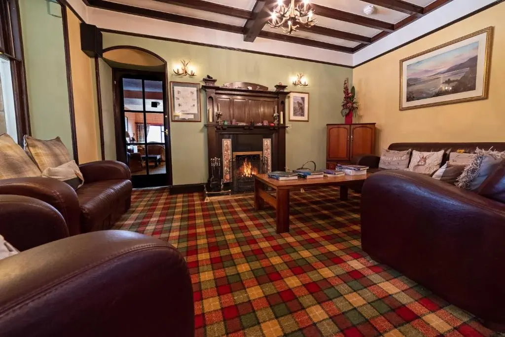 a living room with leather furniture and a fireplace at The Rowan Tree Country Hotel in Aviemore