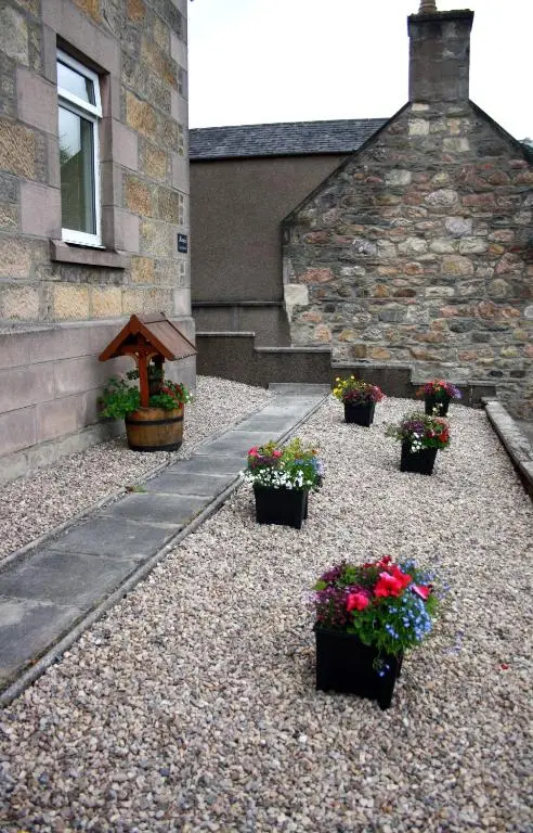 a group of potted plants sitting in front of a building at Mary's Apartment in Rothes