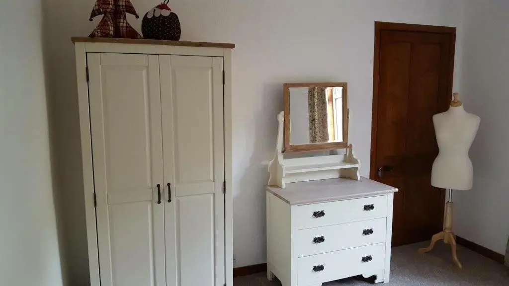 a bedroom with a white cabinet and a mirror at Mary's Apartment in Rothes
