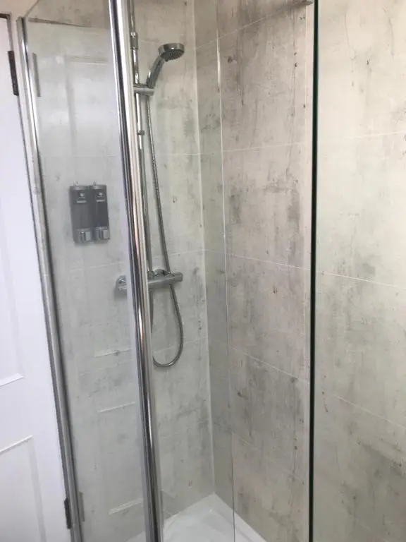 a shower stall with a glass door with a shower at Garfield Guesthouse in Dingwall