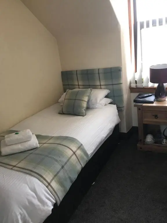 a small bedroom with a bed and a window at Garfield Guesthouse in Dingwall