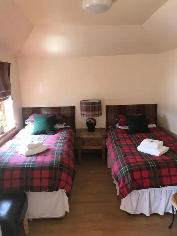 a bedroom with two beds and a night stand at Garfield Guesthouse in Dingwall