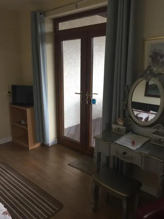 a room with a mirror and a dressing table and a door at Doura Lodge in Inverness