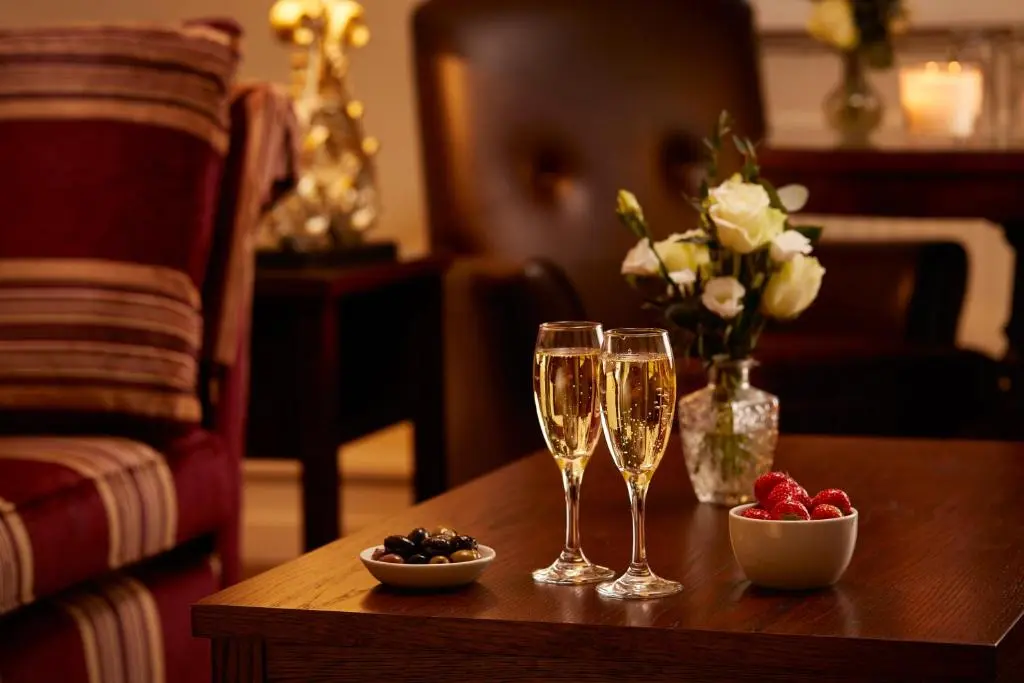 a table with two champagne glasses and a vase of flowers at Macdonald Highlands Hotel at Macdonald Aviemore Resort in Aviemore