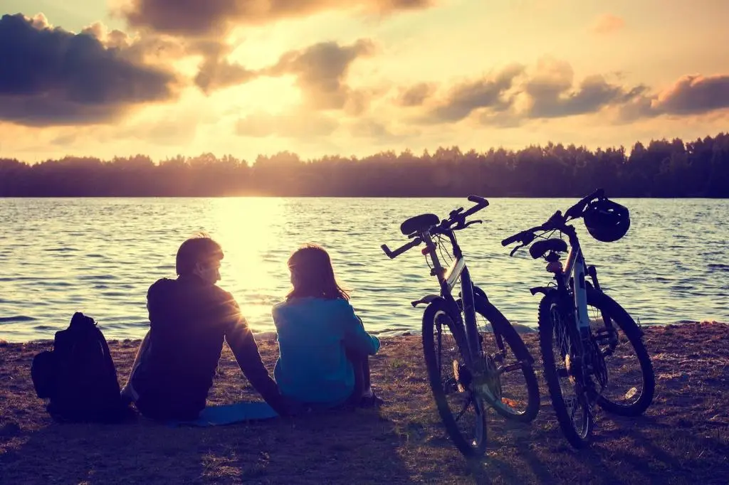 a man and a woman sitting on the beach with bikes at Macdonald Highlands Hotel at Macdonald Aviemore Resort in Aviemore