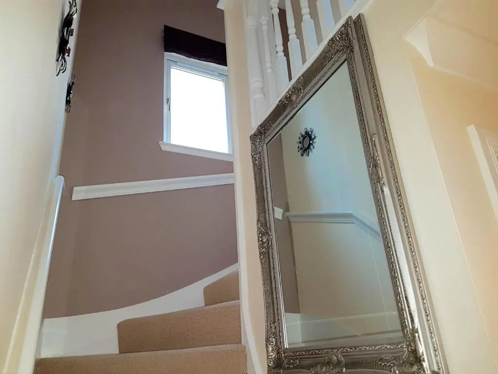 a mirror in a hallway next to a staircase at Jane's Villa Free Parking in Inverness