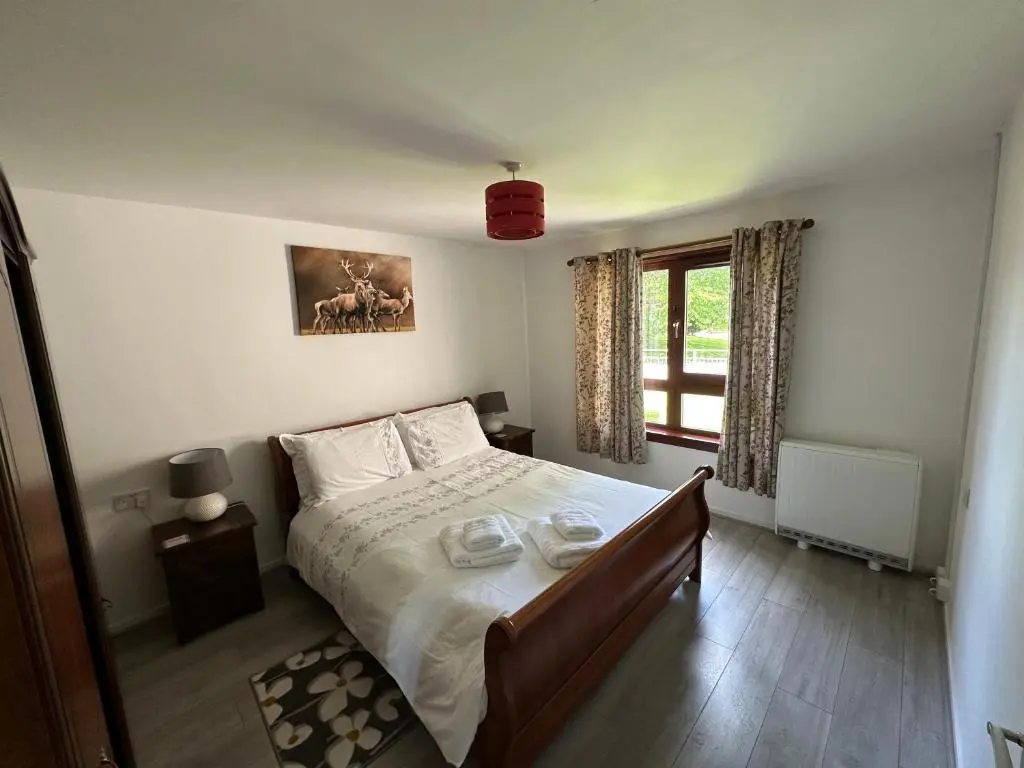 a bedroom with a large bed and a window at Coppice Cottage in Grantown on Spey
