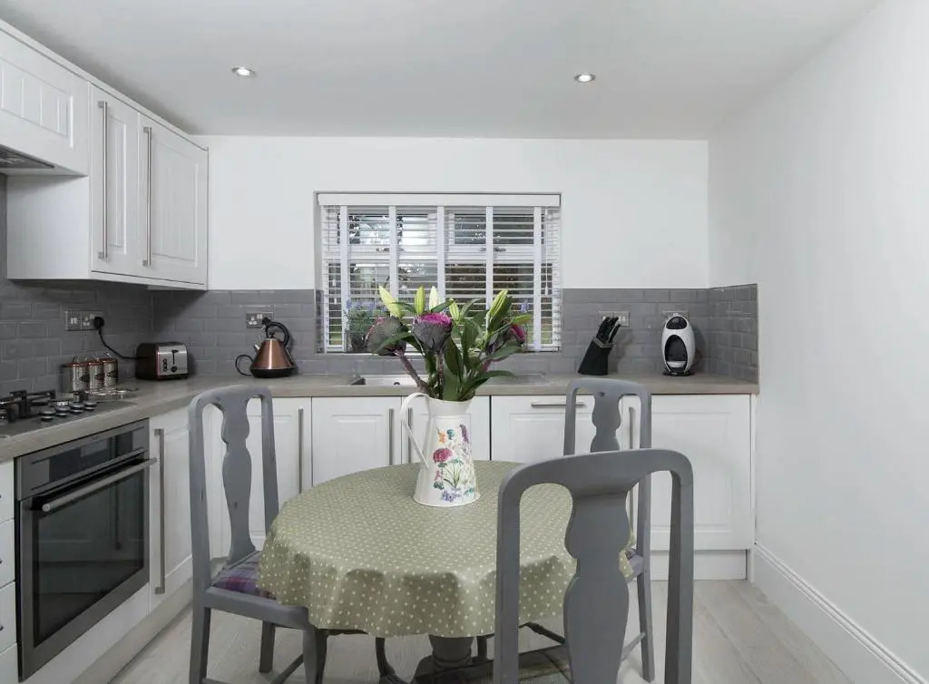 a kitchen with a table with chairs and a vase with flowers at Firlands Lodge in Forres