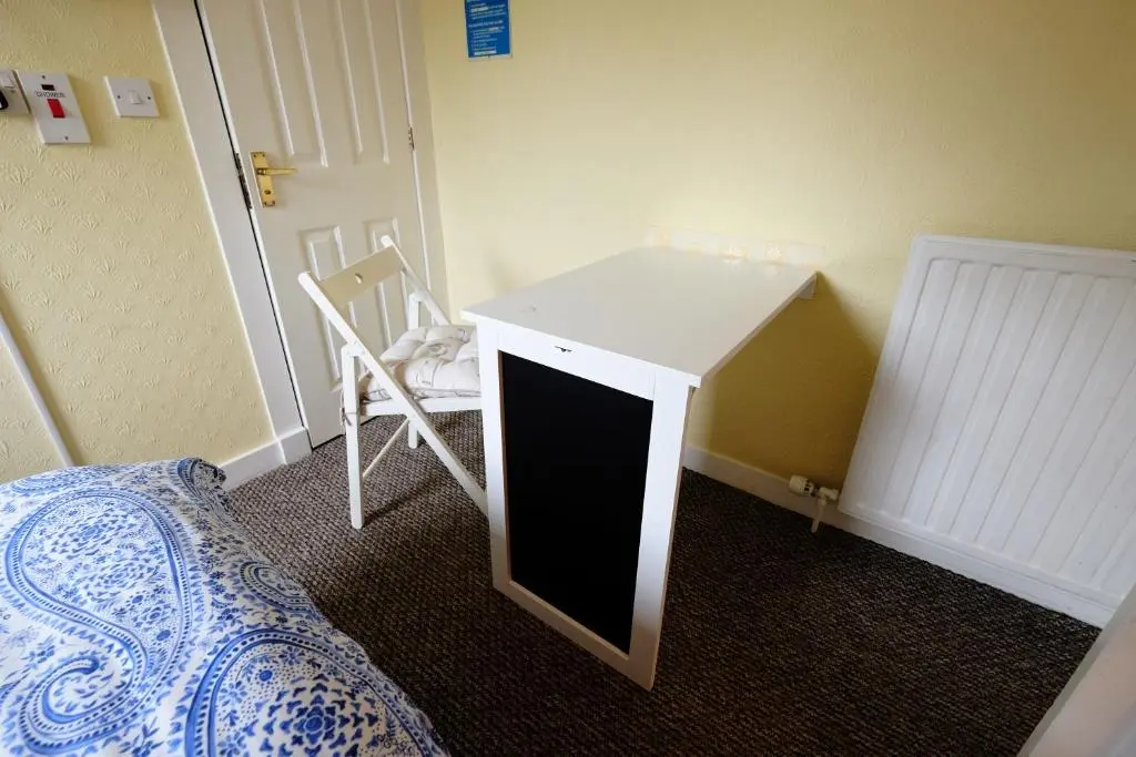 a small desk in a room with a bed and a table at Talisker Guest House in Inverness